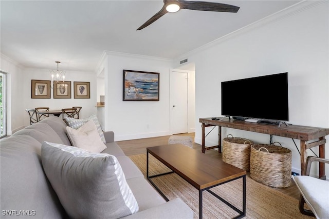 living room featuring wood-type flooring, ceiling fan with notable chandelier, and crown molding