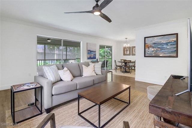 living room featuring ceiling fan with notable chandelier, ornamental molding, and light hardwood / wood-style floors