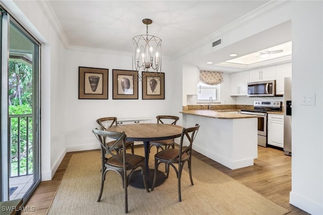 dining area with an inviting chandelier, sink, crown molding, and light wood-type flooring