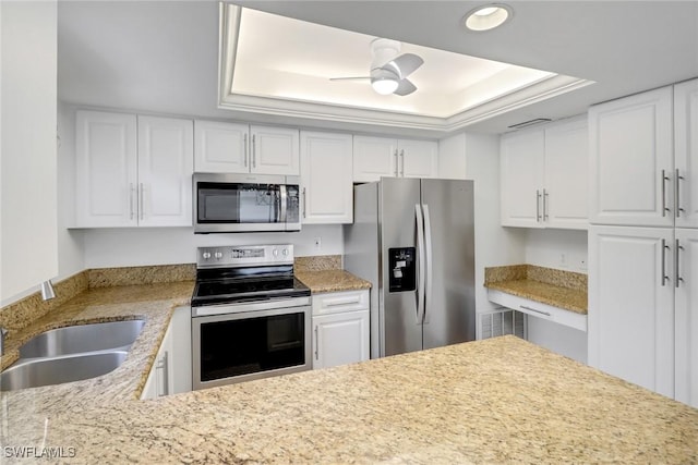 kitchen with ceiling fan, a tray ceiling, white cabinets, and appliances with stainless steel finishes