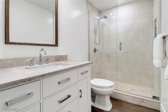 bathroom featuring wood-type flooring, a shower with shower door, vanity, and toilet