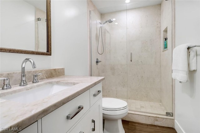 bathroom featuring vanity, toilet, a shower with shower door, and wood-type flooring