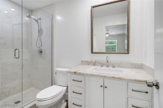 bathroom featuring ceiling fan, vanity, toilet, and a shower with shower door