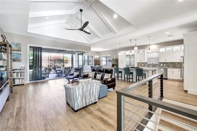 living room featuring ceiling fan, lofted ceiling with beams, and light hardwood / wood-style flooring