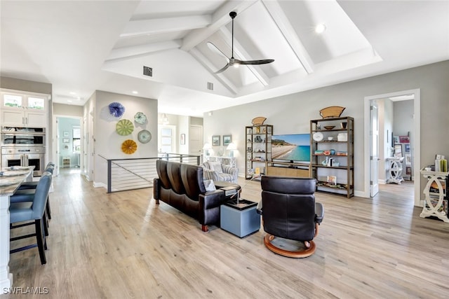 living room featuring ceiling fan, high vaulted ceiling, beamed ceiling, and light hardwood / wood-style flooring