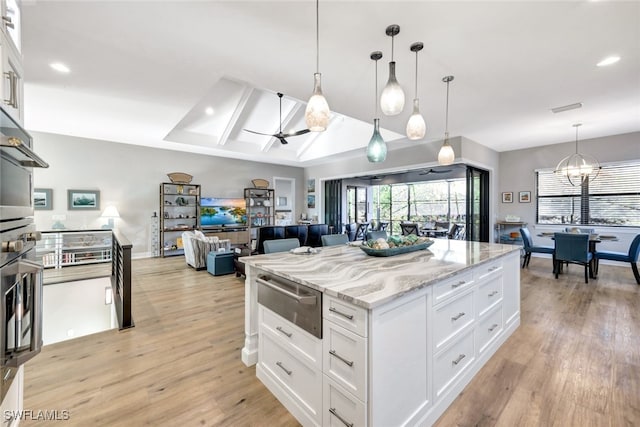 kitchen with white cabinetry, pendant lighting, ceiling fan with notable chandelier, and light stone counters