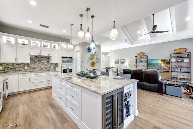 kitchen with wine cooler, white cabinets, tasteful backsplash, and a kitchen island