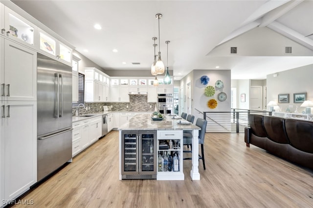 kitchen featuring appliances with stainless steel finishes, beverage cooler, white cabinets, and a center island