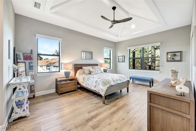 bedroom featuring a raised ceiling, ceiling fan, and light wood-type flooring