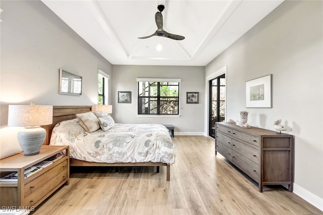 bedroom featuring ceiling fan, a tray ceiling, and light hardwood / wood-style flooring