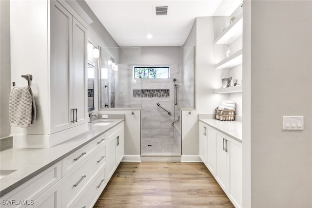 bathroom with vanity, wood-type flooring, and tiled shower