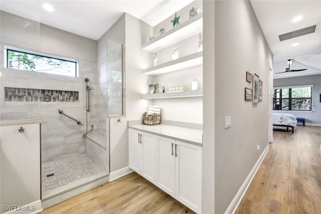 bathroom with hardwood / wood-style flooring, tiled shower, vanity, and ceiling fan