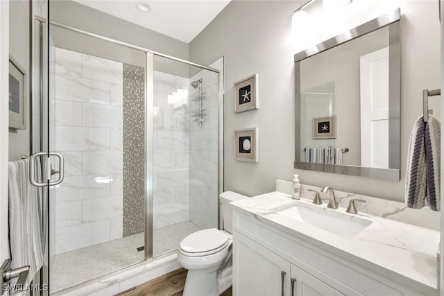 bathroom featuring wood-type flooring, an enclosed shower, vanity, and toilet