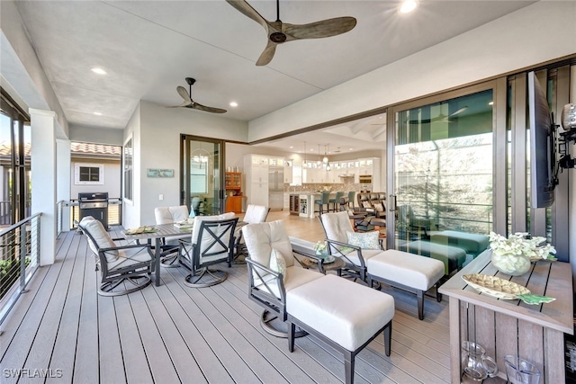 wooden deck with ceiling fan and area for grilling