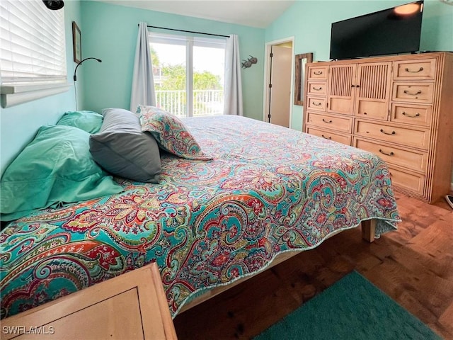 bedroom with lofted ceiling and access to outside