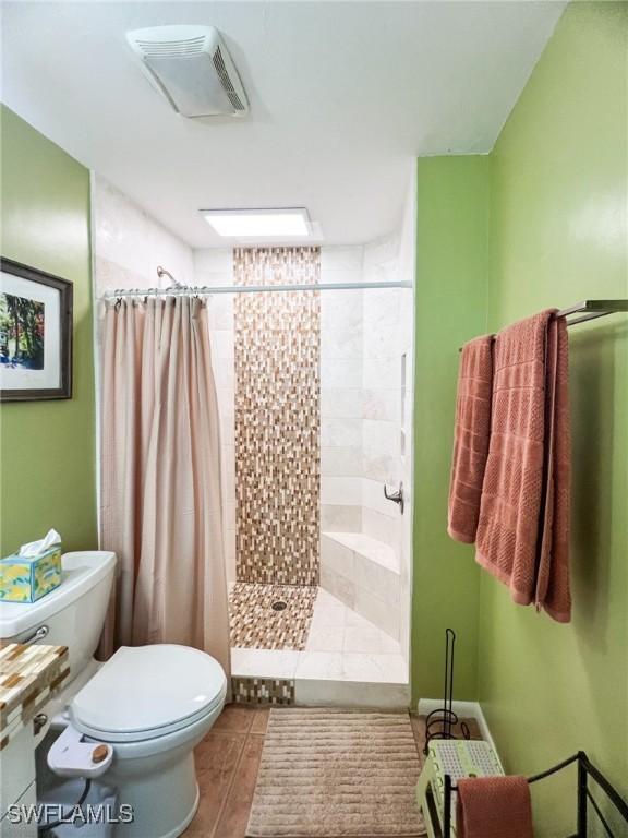 bathroom featuring tile patterned flooring, a shower with curtain, and toilet