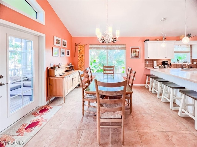 dining space with vaulted ceiling, light tile patterned floors, sink, and a chandelier