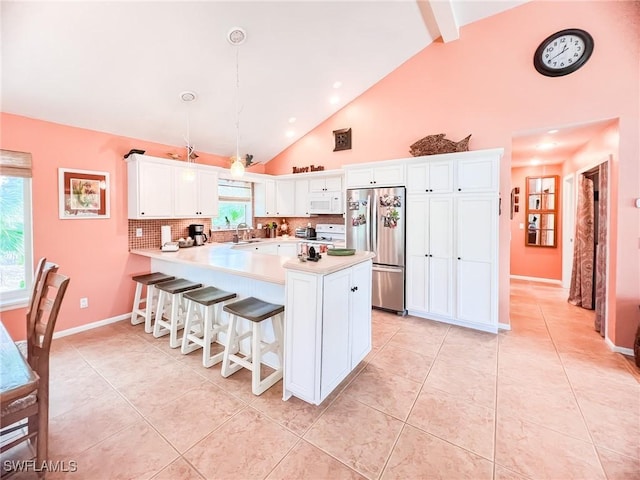 kitchen with sink, hanging light fixtures, tasteful backsplash, kitchen peninsula, and stainless steel refrigerator