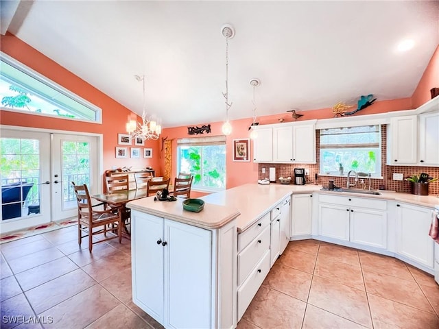 kitchen featuring kitchen peninsula, hanging light fixtures, lofted ceiling, and sink