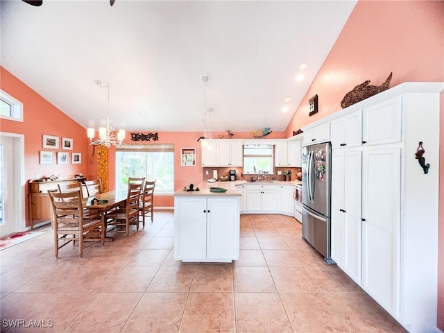 kitchen featuring a center island, high vaulted ceiling, decorative light fixtures, white cabinetry, and stainless steel refrigerator