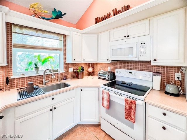 kitchen with backsplash, white appliances, light tile patterned floors, white cabinetry, and lofted ceiling