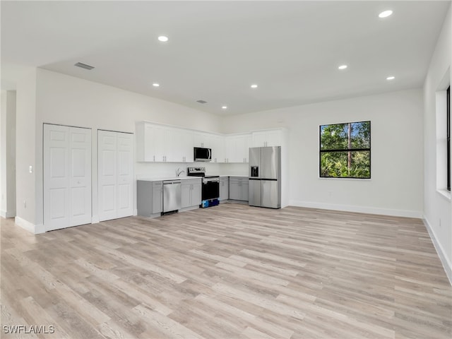 kitchen with white cabinets, stainless steel appliances, and light hardwood / wood-style floors