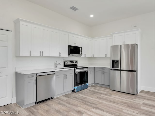 kitchen with sink, light hardwood / wood-style flooring, gray cabinets, appliances with stainless steel finishes, and white cabinetry