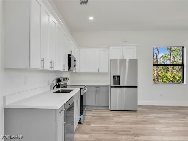 kitchen with light hardwood / wood-style floors, sink, white cabinetry, and stainless steel appliances