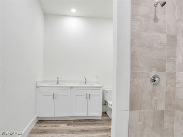 bathroom featuring tiled shower, toilet, vanity, and hardwood / wood-style flooring