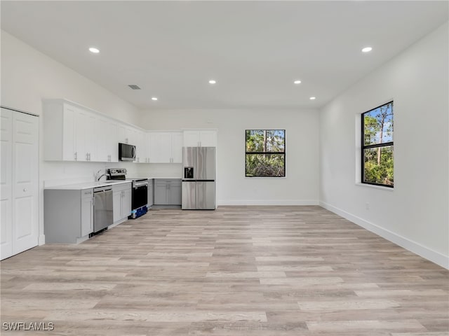 kitchen featuring white cabinets, light hardwood / wood-style floors, a healthy amount of sunlight, and appliances with stainless steel finishes