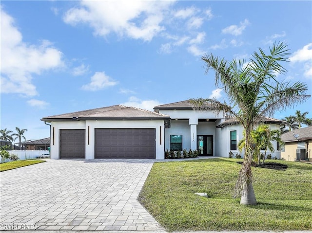 prairie-style house featuring stucco siding, a front yard, decorative driveway, and a garage