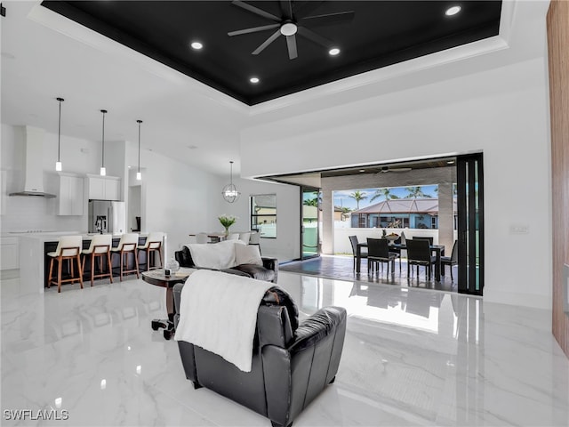 living room featuring crown molding, a tray ceiling, and ceiling fan