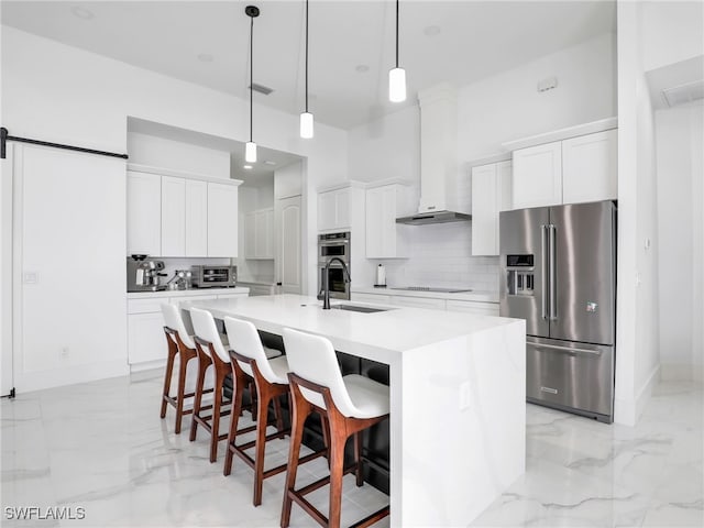 kitchen featuring sink, wall chimney range hood, stainless steel appliances, white cabinets, and an island with sink