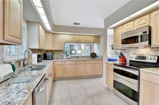 kitchen featuring sink, a healthy amount of sunlight, light tile patterned floors, and appliances with stainless steel finishes