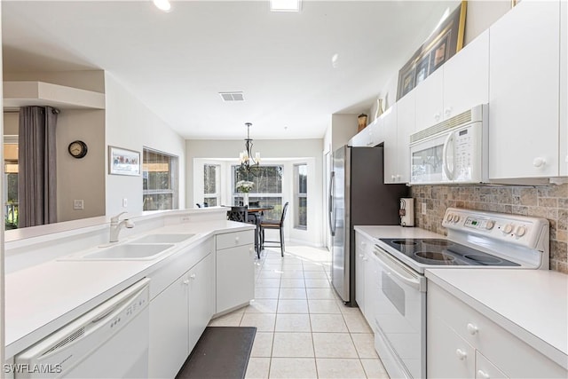 kitchen with white appliances, white cabinets, decorative light fixtures, light countertops, and a sink