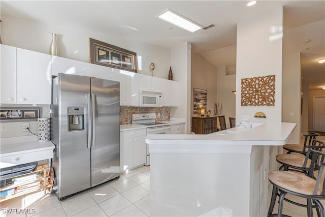 kitchen with white appliances, visible vents, white cabinets, light countertops, and a kitchen bar