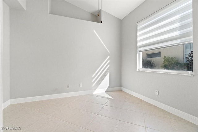 empty room with light tile patterned flooring and vaulted ceiling