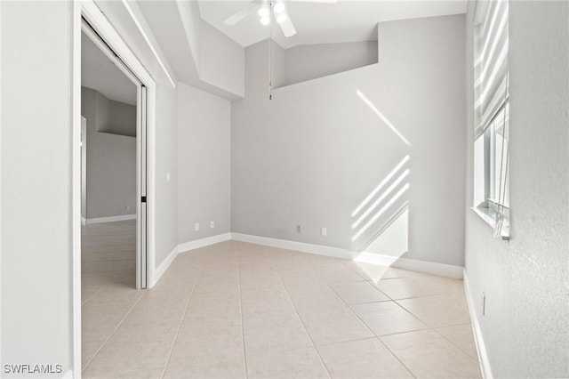 tiled empty room with ceiling fan and vaulted ceiling