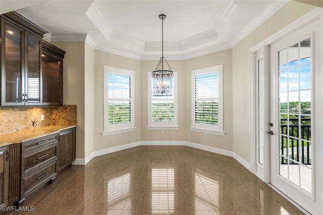 dining space with a raised ceiling, crown molding, and an inviting chandelier