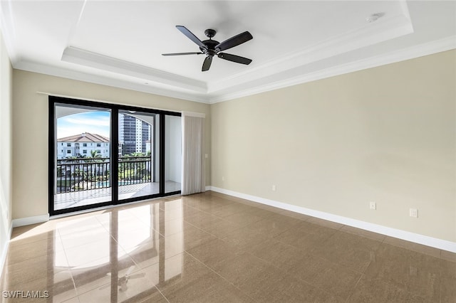 empty room featuring a tray ceiling, ornamental molding, and ceiling fan