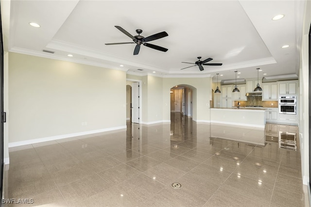 unfurnished living room with a raised ceiling, crown molding, and ceiling fan