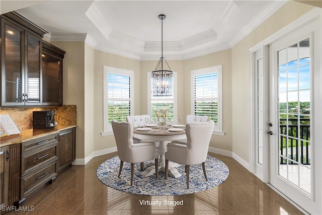 dining space with crown molding, a healthy amount of sunlight, a notable chandelier, and a tray ceiling