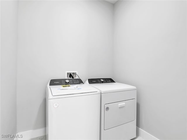 clothes washing area featuring laundry area, baseboards, and separate washer and dryer