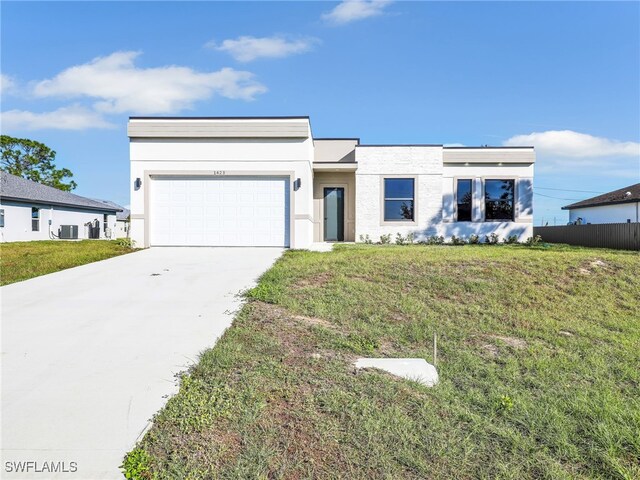 view of front facade featuring a garage, a front yard, and central air condition unit