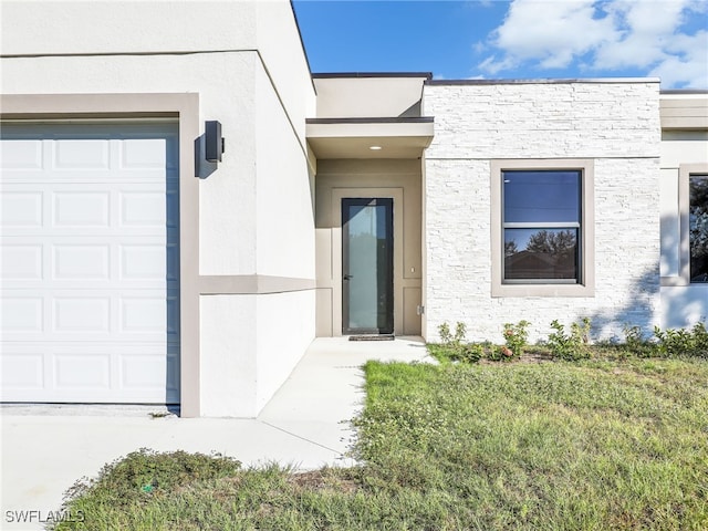 view of exterior entry with a garage and stucco siding