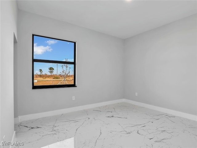 spare room with marble finish floor and baseboards