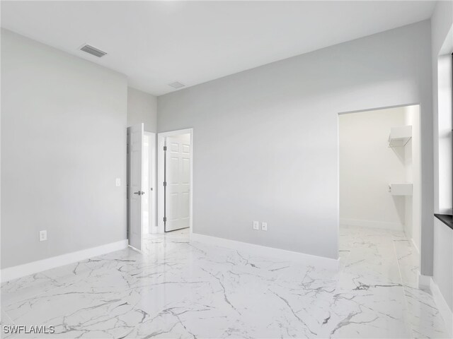 empty room with marble finish floor, visible vents, and baseboards