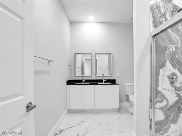 full bath featuring toilet, double vanity, a marble finish shower, and baseboards