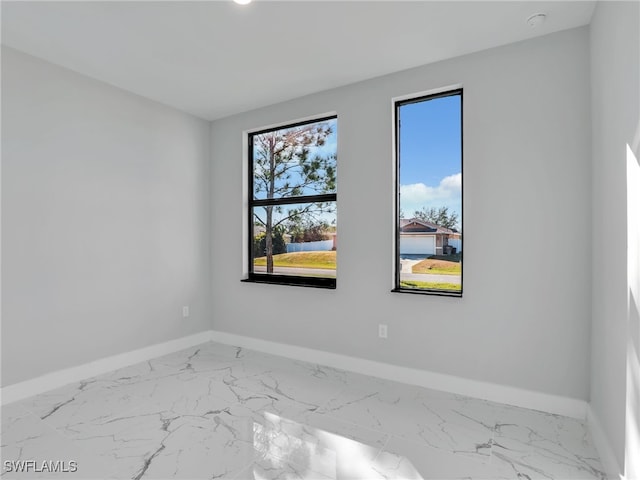 unfurnished room featuring marble finish floor and baseboards