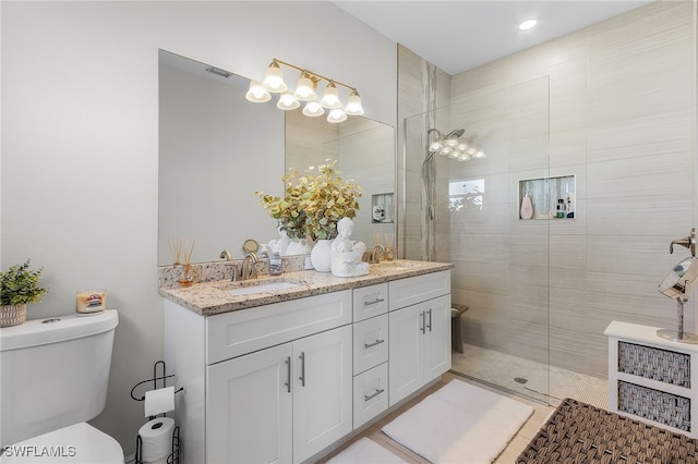 bathroom featuring vanity, toilet, and a tile shower